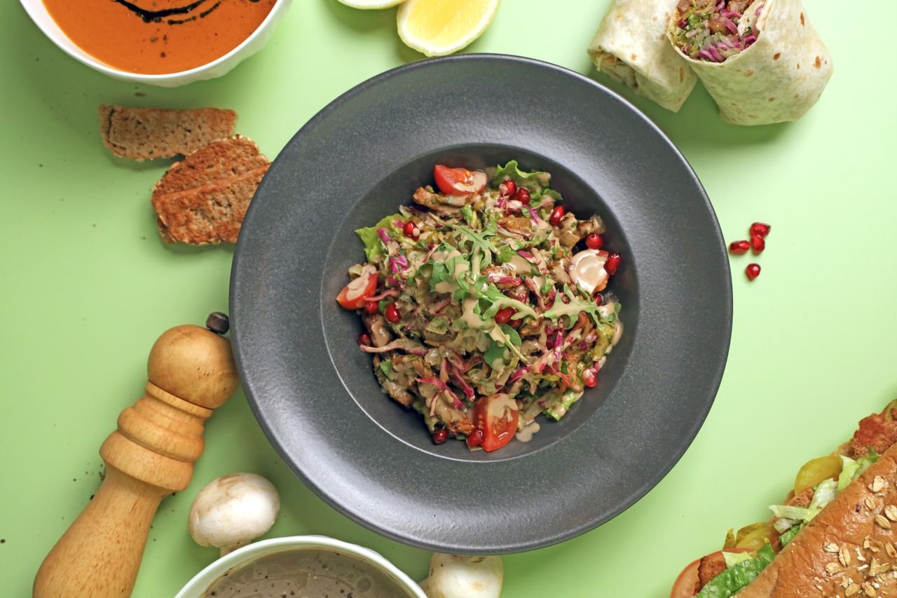 Colorful healthy Mediterranean salad with pomegranate and wraps on a vibrant background.