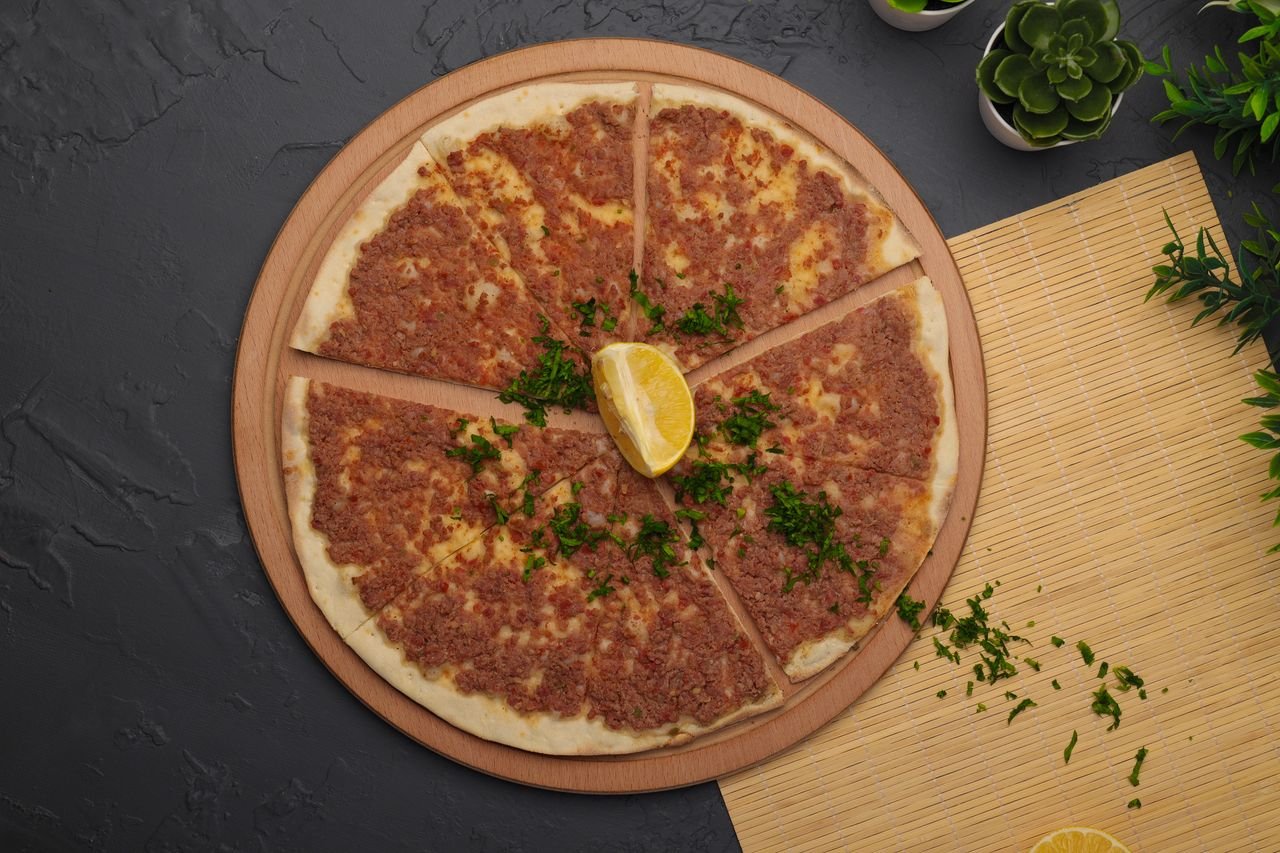 Delicious Turkish lahmacun topped with herbs and a lemon wedge, ready to serve.